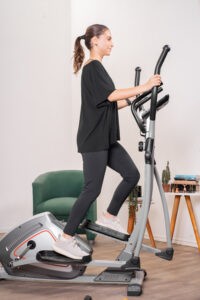 Woman using elliptical machine at home for full-body workout
